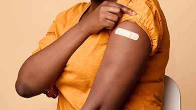 Closeup of black woman arm with bandaid.