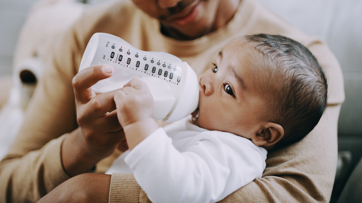 Parent feeding infant a bottle of formula