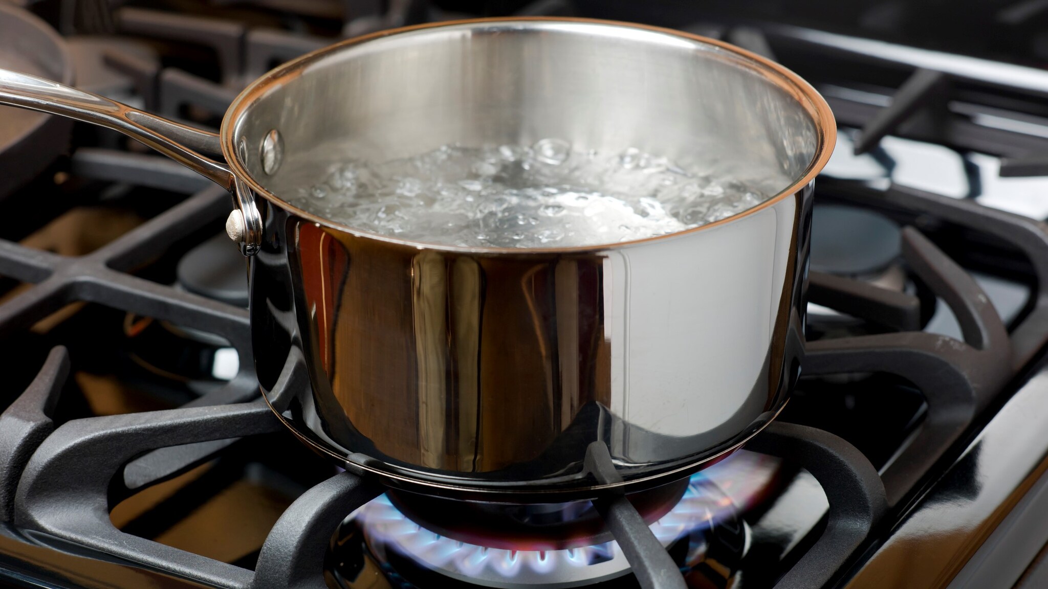 Boiling water in a pan being heated on a stove.