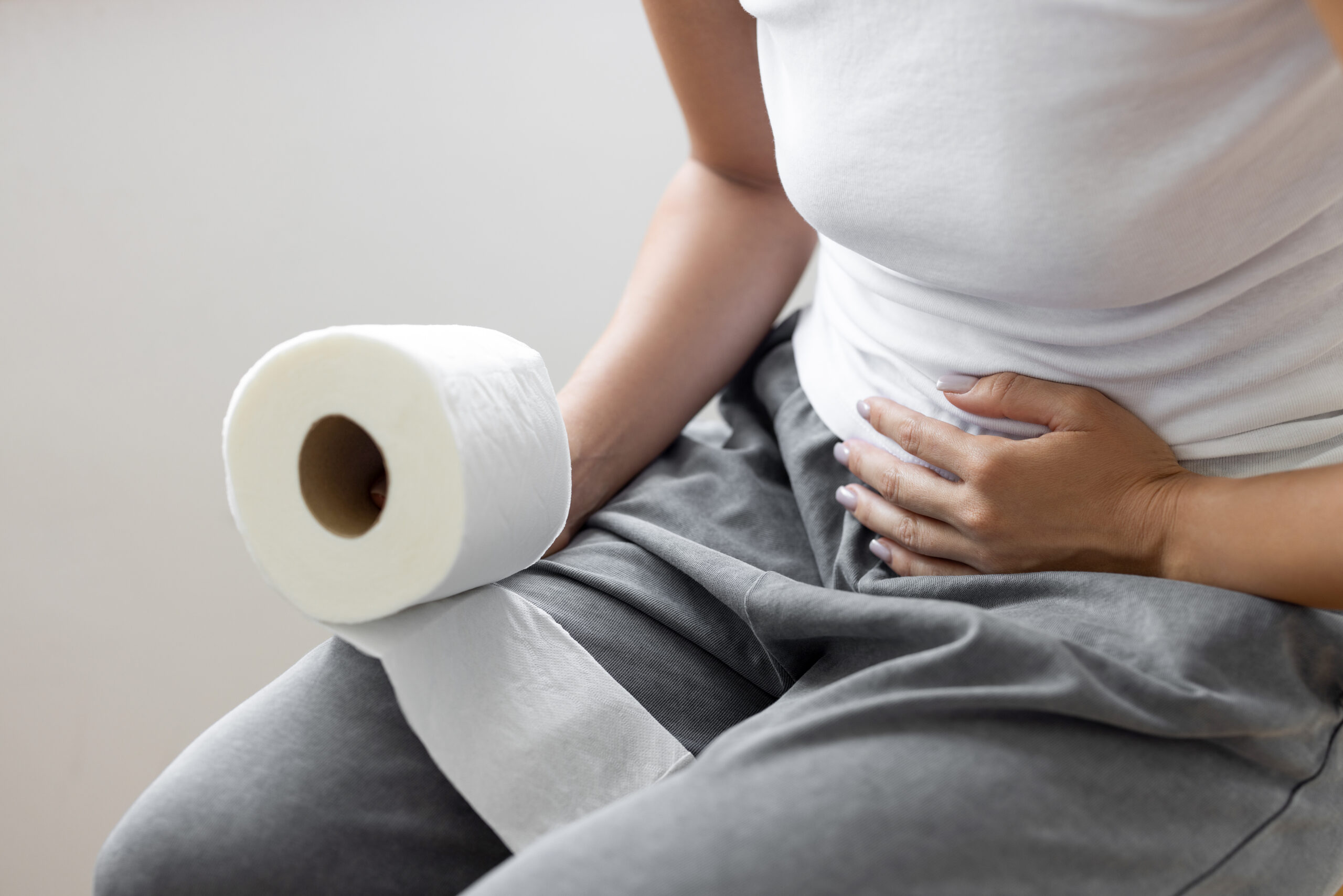 Person sitting with stomach pain and toilet paper