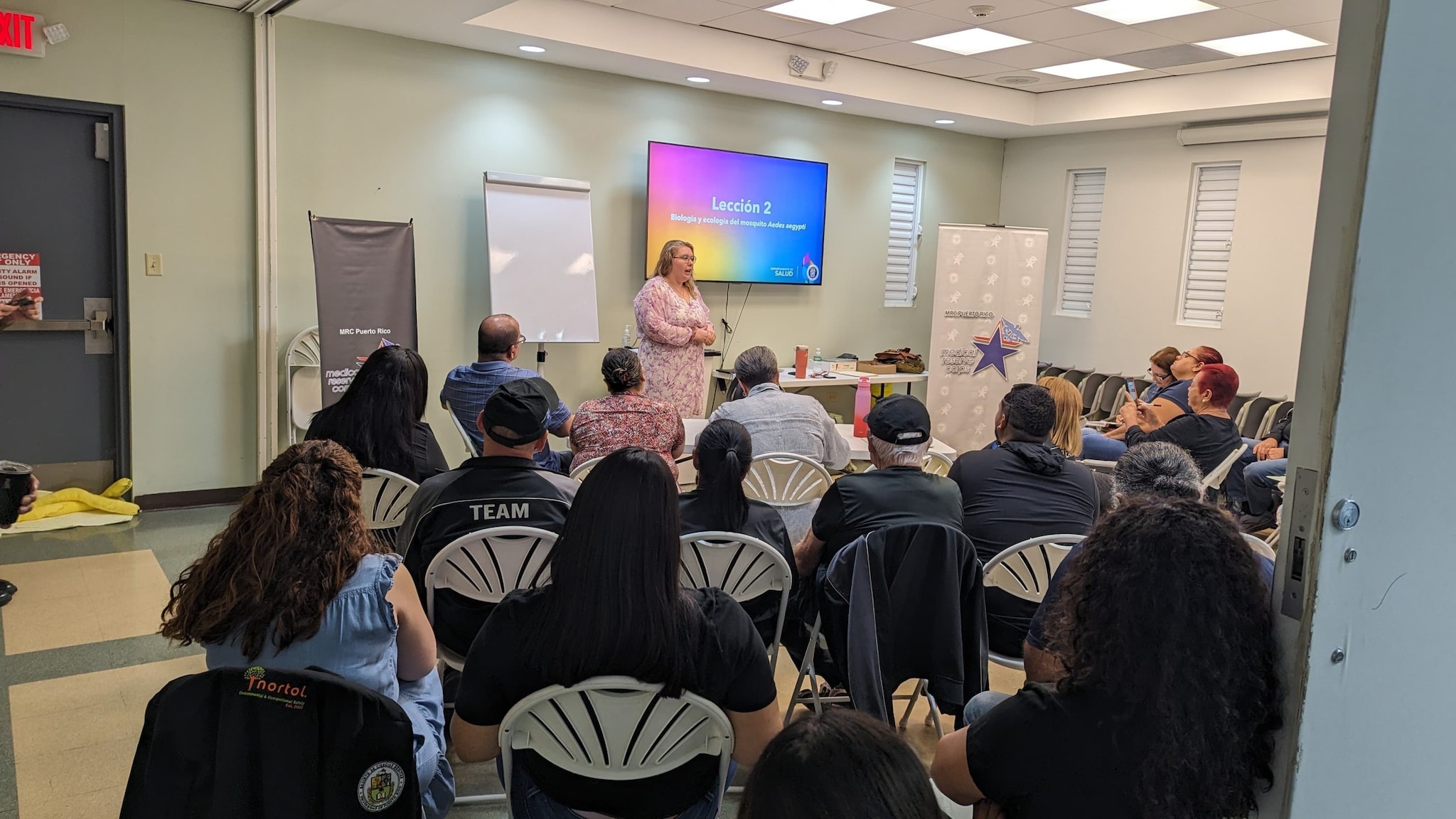 A person presenting in front of a room of seated people.