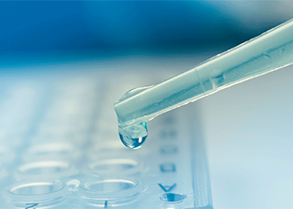 An image of a pipette dropping a liquid into a test tray.