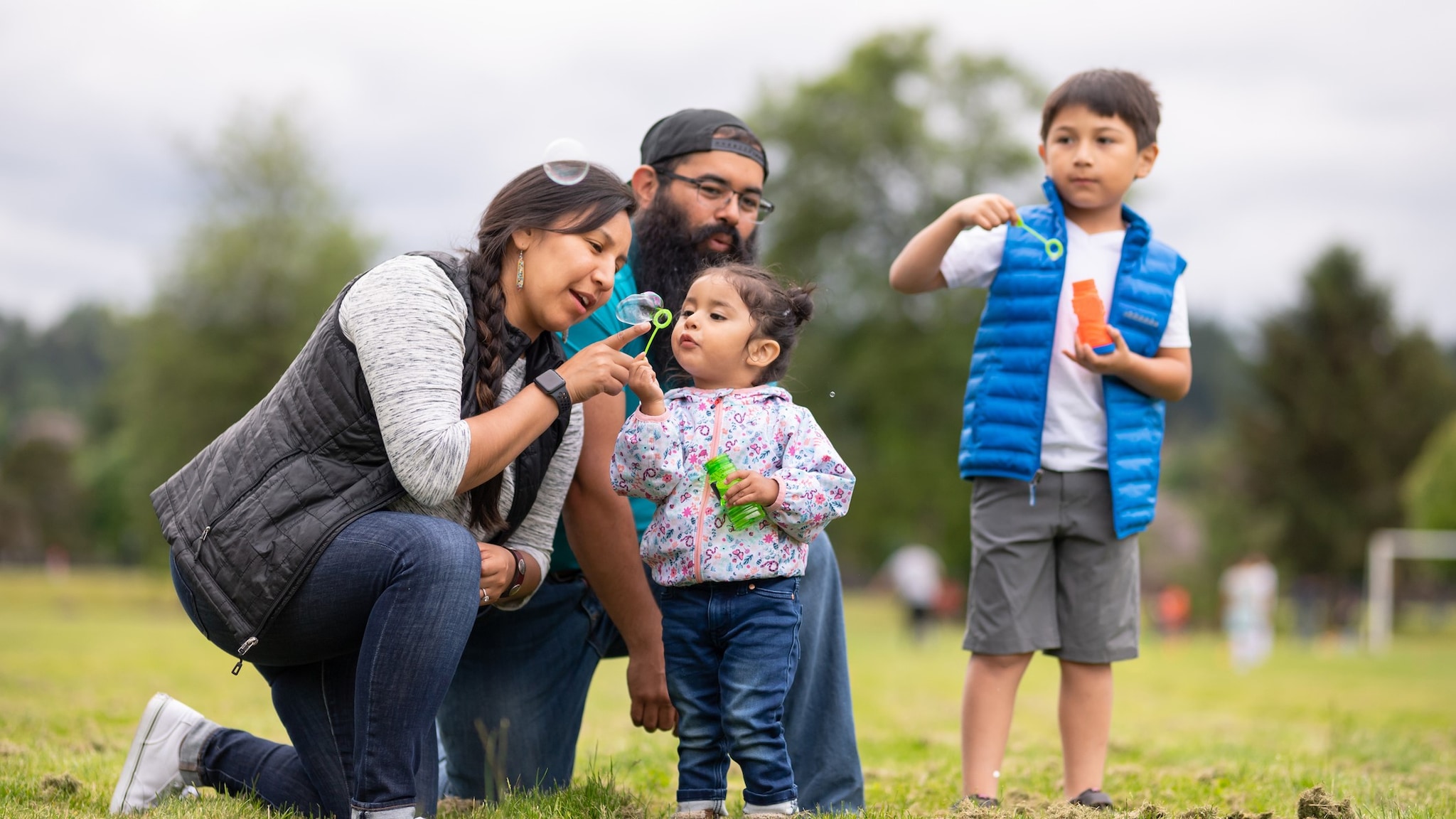 Native American family blowing bubbles at a park
