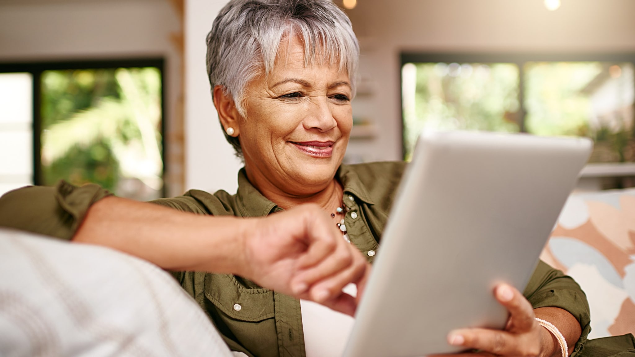 Older adult woman smiling and looking at her tablet