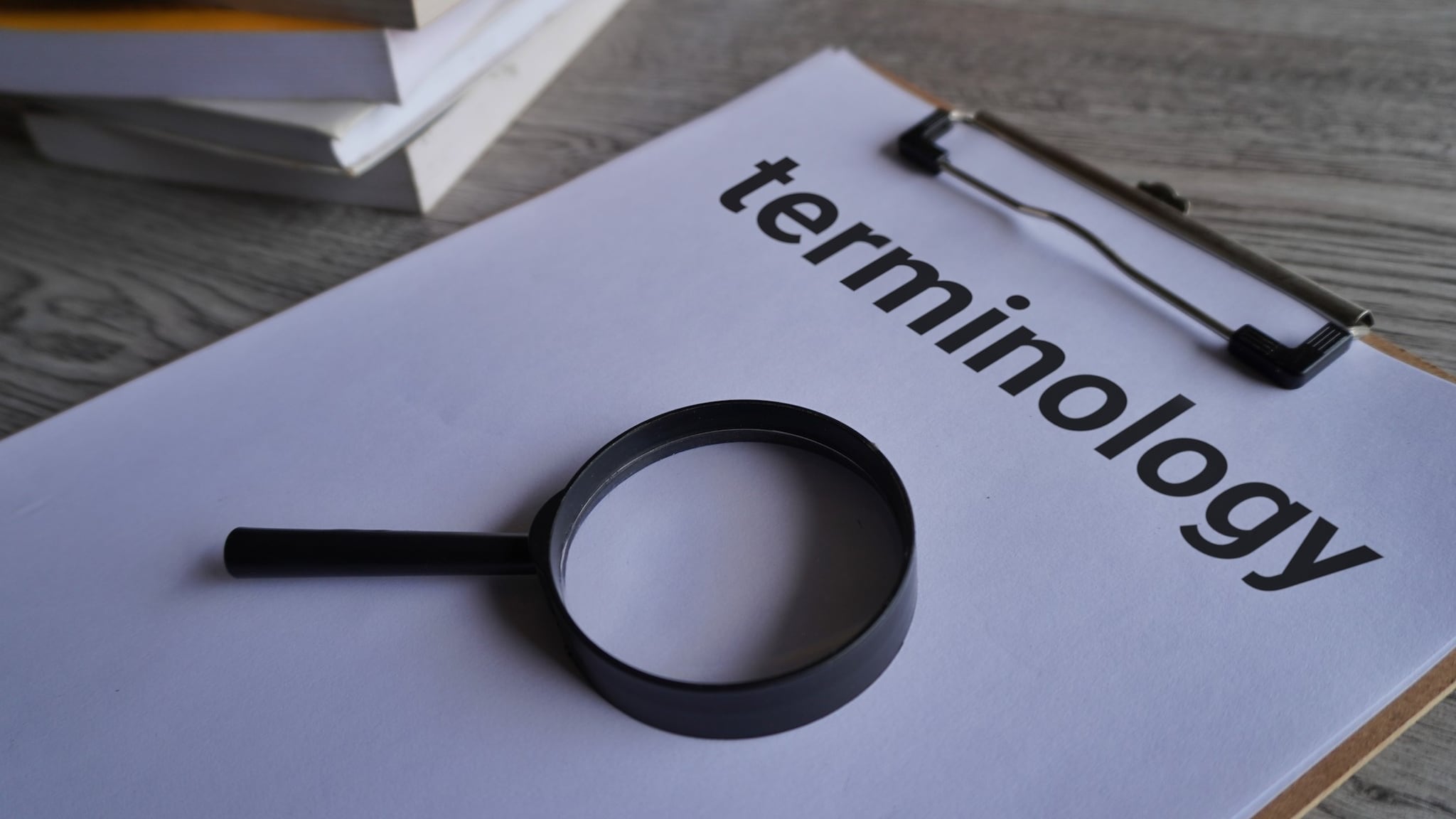 Magnifying glass and clipboard with paper and the word "terminology"
