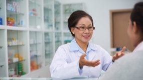 Pharmacist talking with patient at counter.