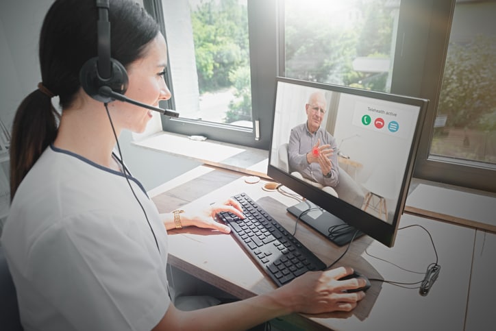 Woman with headset having a telehealth visit with a man using a laptop.