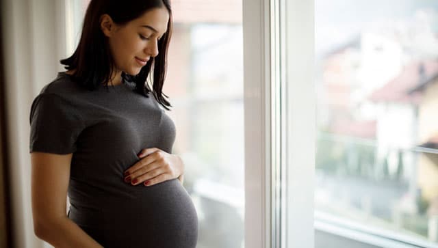 Una mujer embarazada mirándose el vientre.