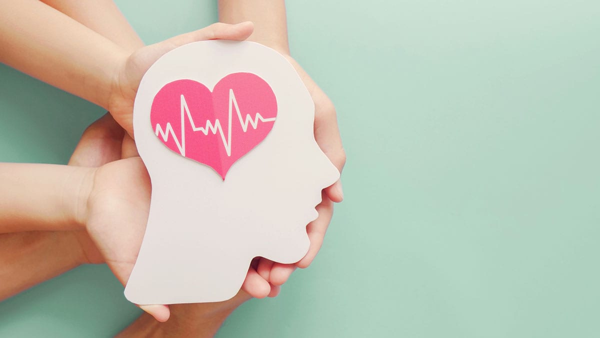 Group of hands holding a paper heart-shaped brain cut out symbolizing a healthy brain.