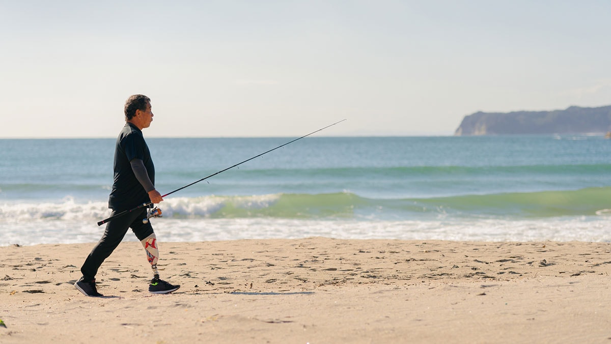 Hombre con una pierna prostética caminando en la playa