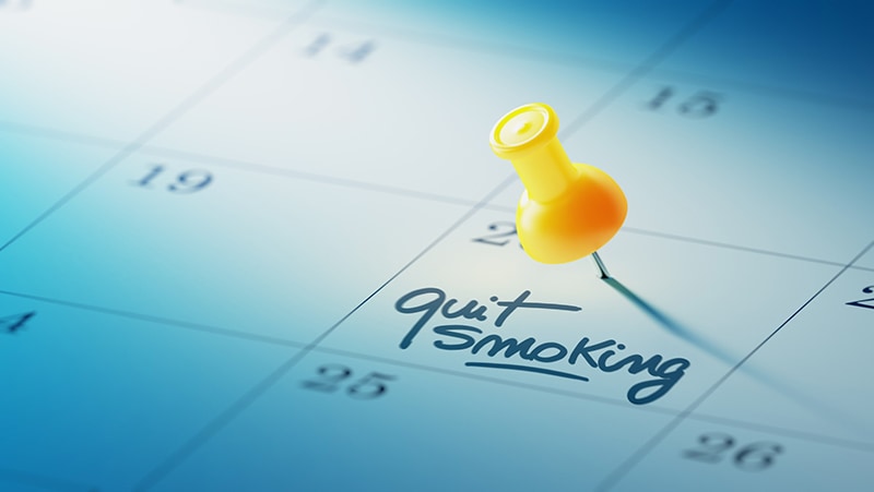 Calendar with yellow pin and 'quit smoking' written as reminder.