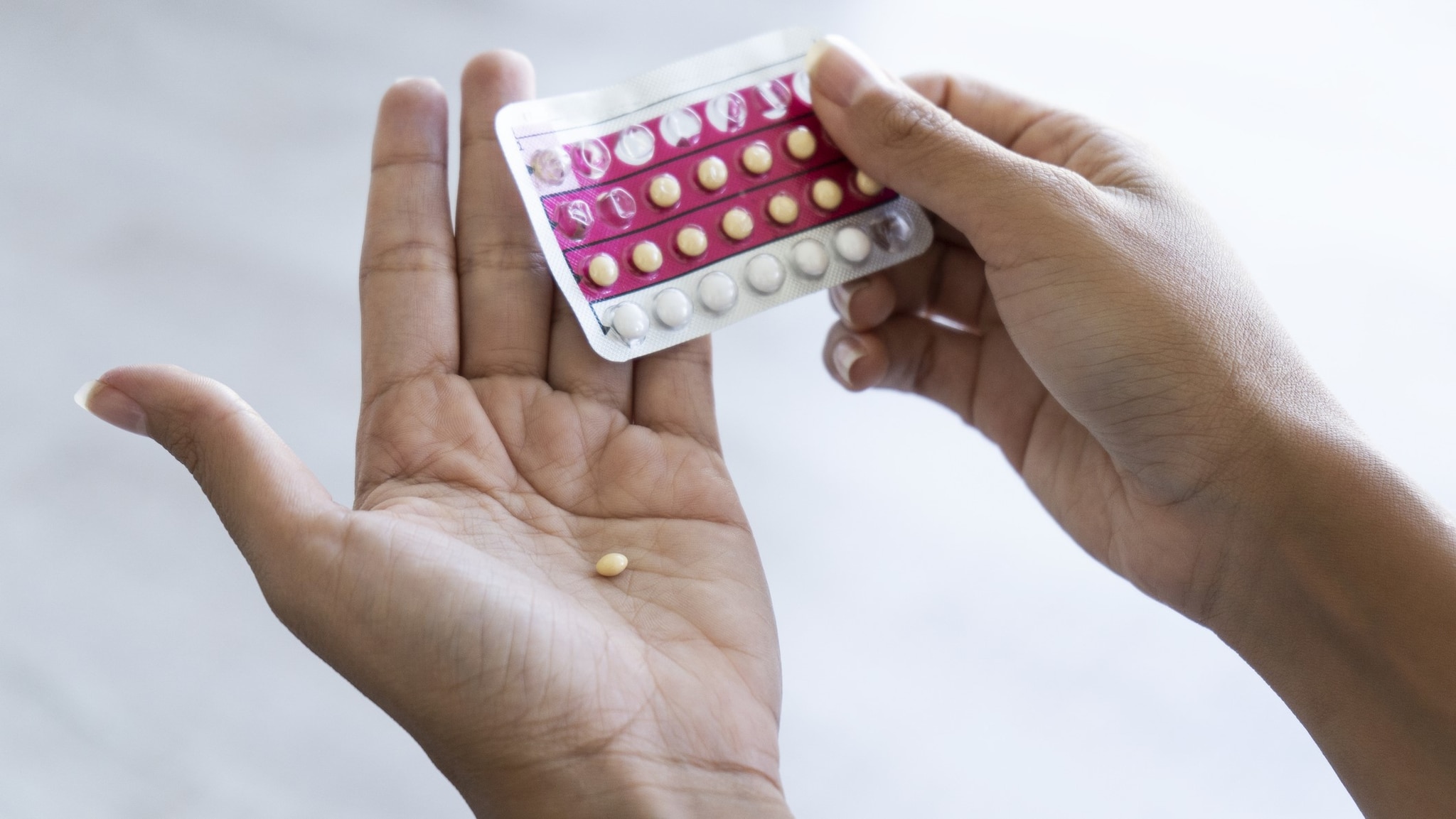 Closeup of a person removing a pill from a pill pack.