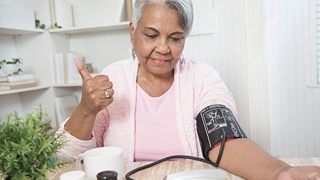 Older woman sitting and checking her blood pressure.