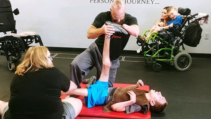 Trainer stretching a boys' legs in gym