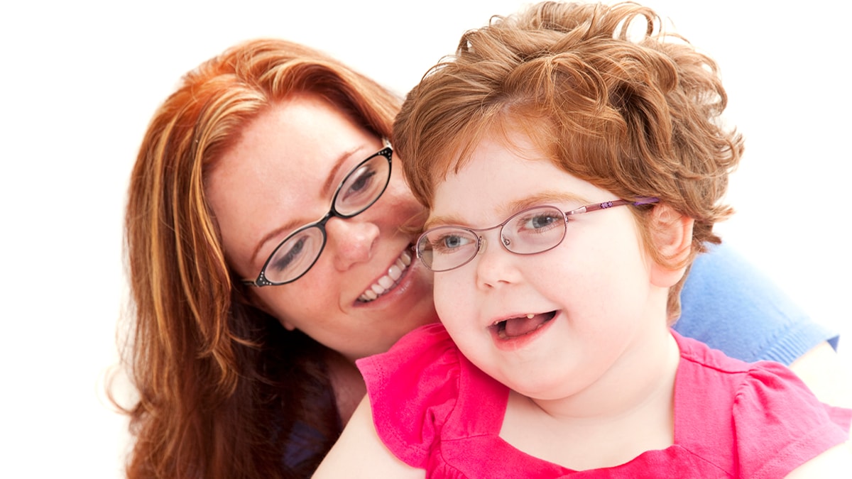 A mother holds a daughter with disabilities.