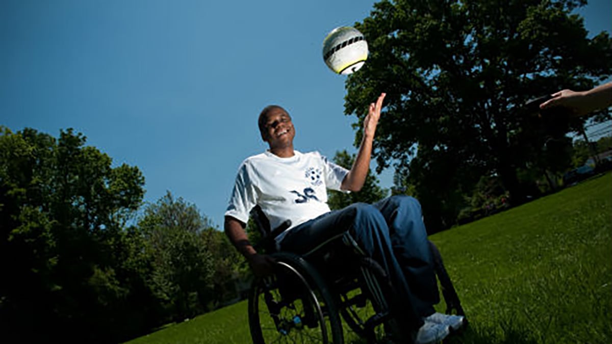 Photo of boy in wheelchair tossing a ball in the air