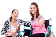 Female friend sitting beside female friend in wheelchair.