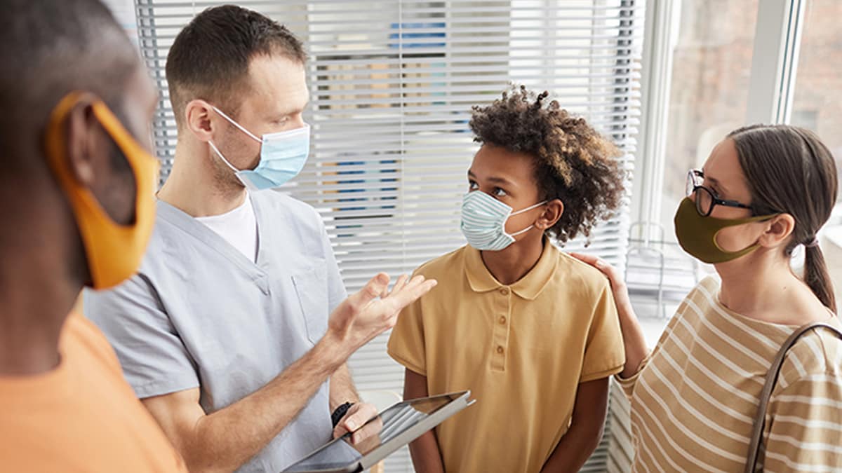 doctor meeting with boy and his parents wearing masks