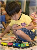 A young child plays with toys near other young children.