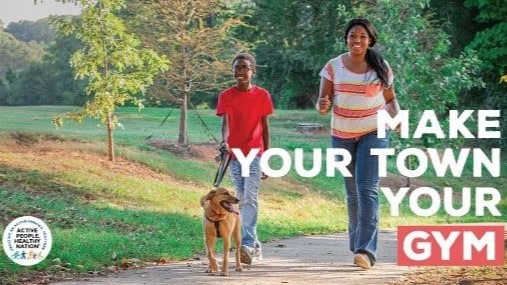 Mother and child walking dog in a park with the text "Make Your Town Your Gym" over the photo.