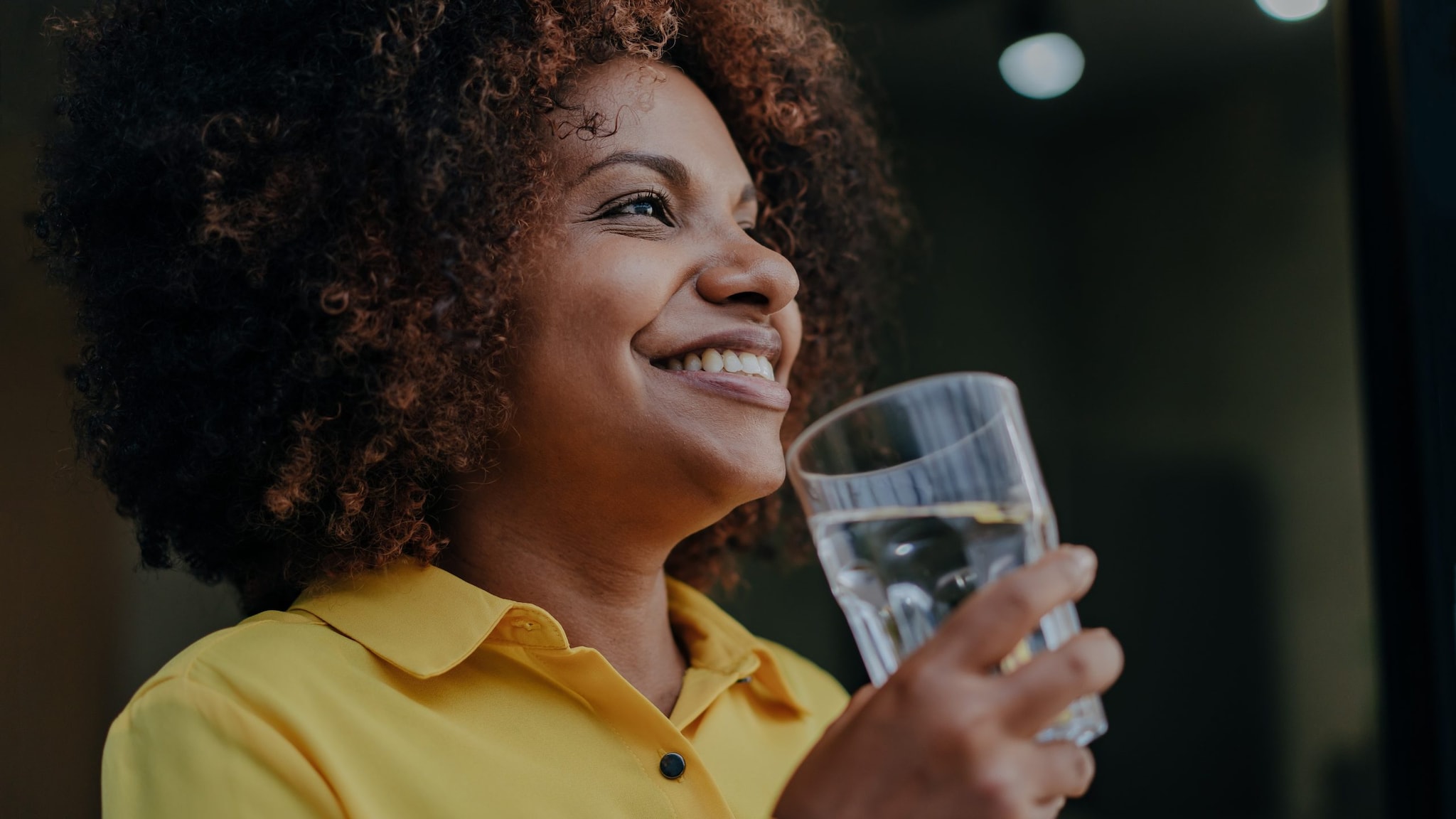 Smiling person holding a glass of water