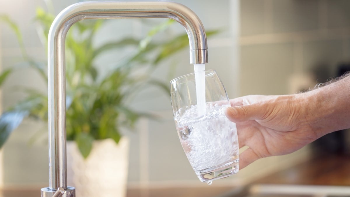 Person filling a glass with tap water from the kitchen sink