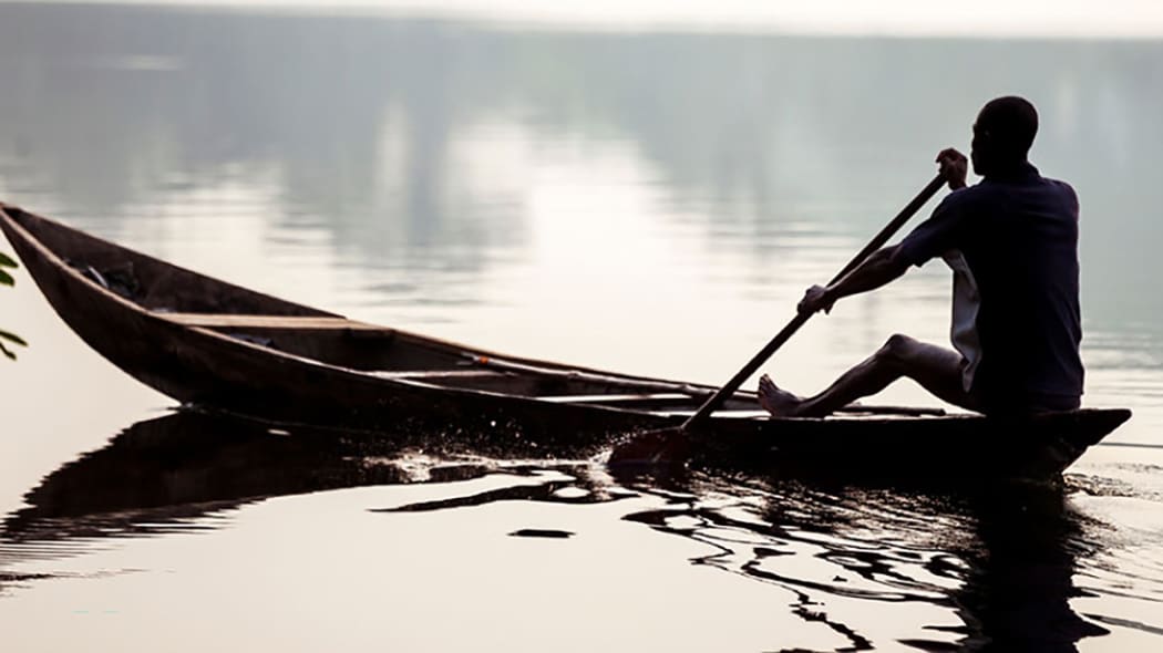 African man rowing a boat on a lake