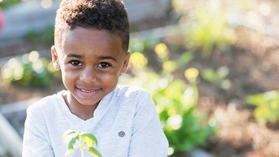 Smiling child holding a plant.
