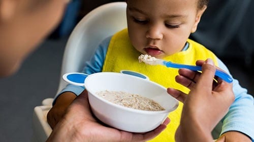 Young child being fed from a bowl.