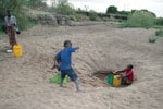 Thumbnail of A family searching for water by digging deep into a dried riverbed during the dry season in northeastern Zambia.