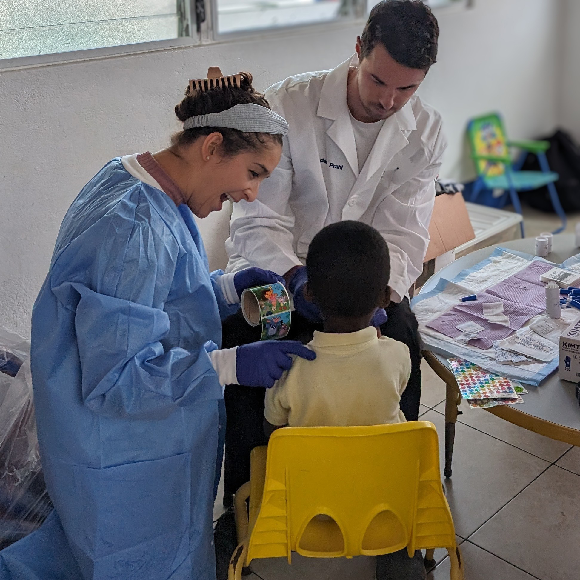 LLS fellow Jordan Prahl (Class of 2023) (right) collects a blood sample from a USVI child for lead testing while LLS fellow Lindsay Hein (Class of 2023) (left) distracts the child with stickers.