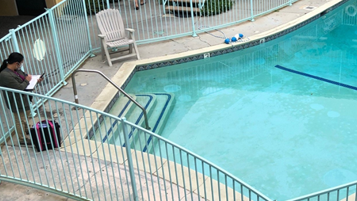 A professional stands by a pool to conduct an inspection.