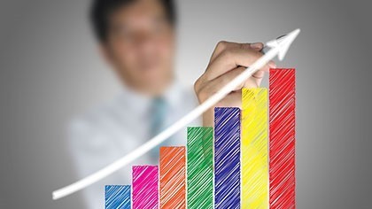 Man draws an upward arrow across a colorful bar chart showing an upward trajectory