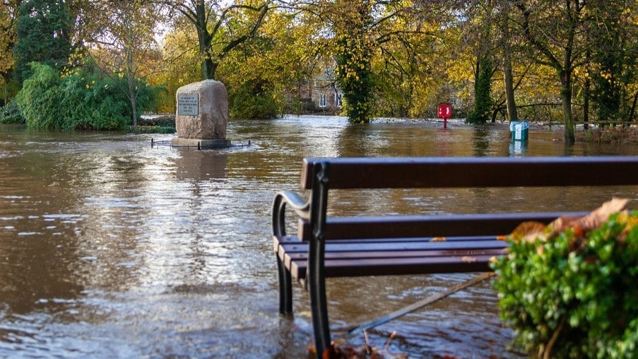 Park bench in the foreground and flood waters all around