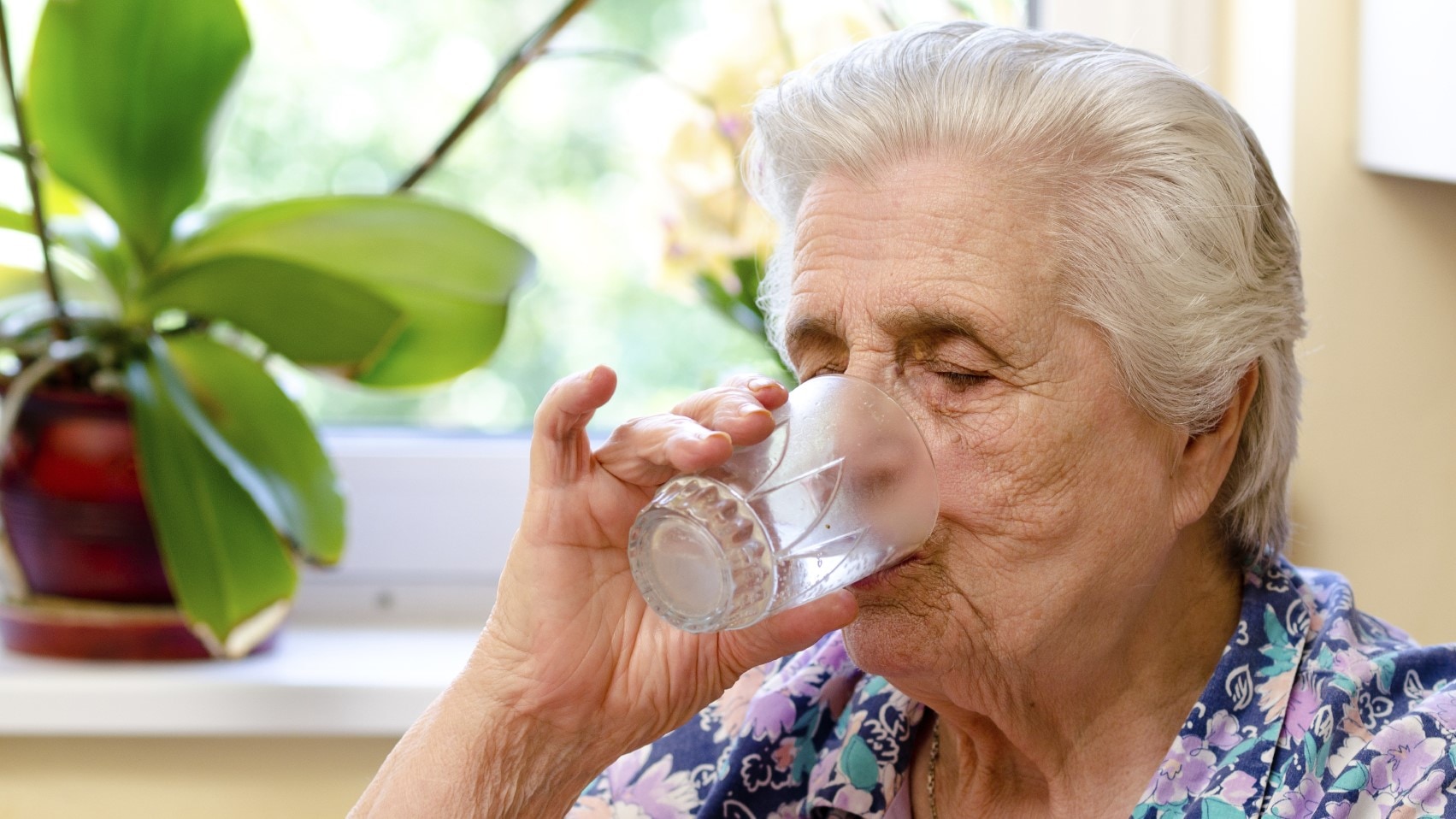 Elderly woman drinking a glass of water.