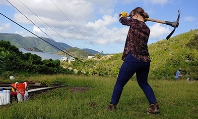 Student swinging a pick axe on a farm