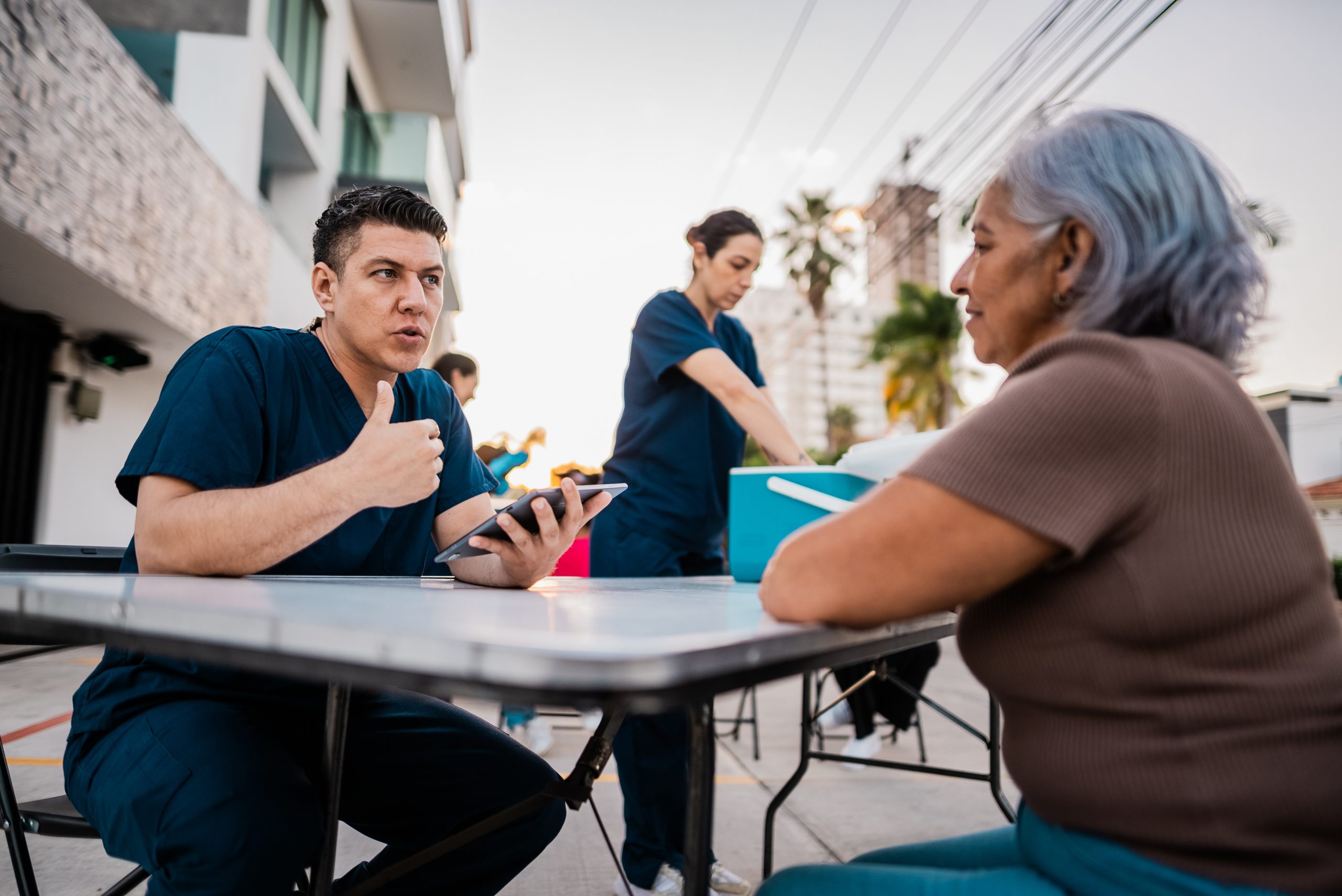 Mid adult nurse man talking to senior woman outdoors.