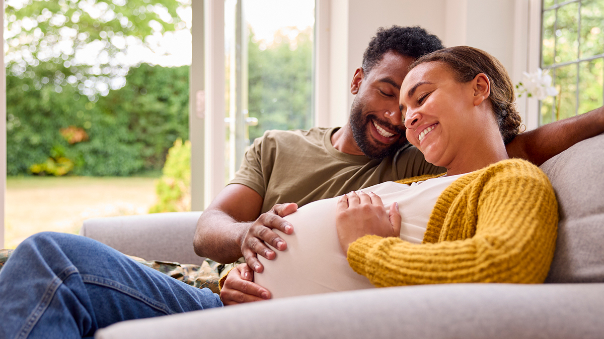 a pregnant woman sitting on a couch with her partner