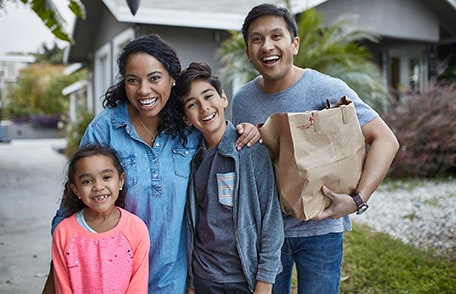 Happy Latino family holding grocery bags