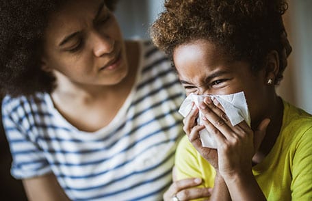 mother holding tissues helping her sick child