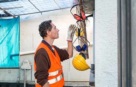 Construction worker reaching for pair of headphones