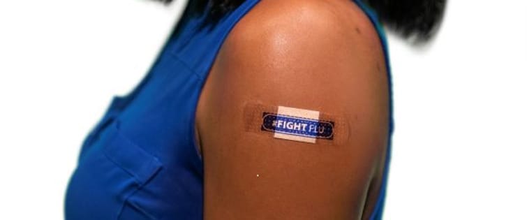 Person after flu shot with band aid with text: #fightflu