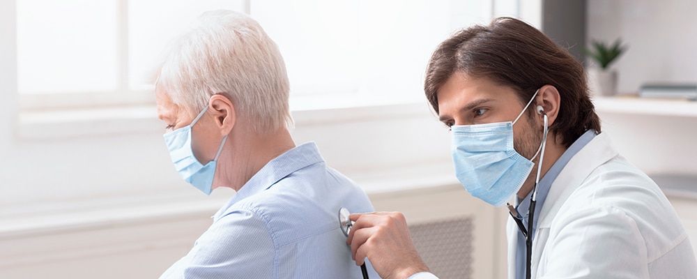 Doctor using stethoscope on woman's back.