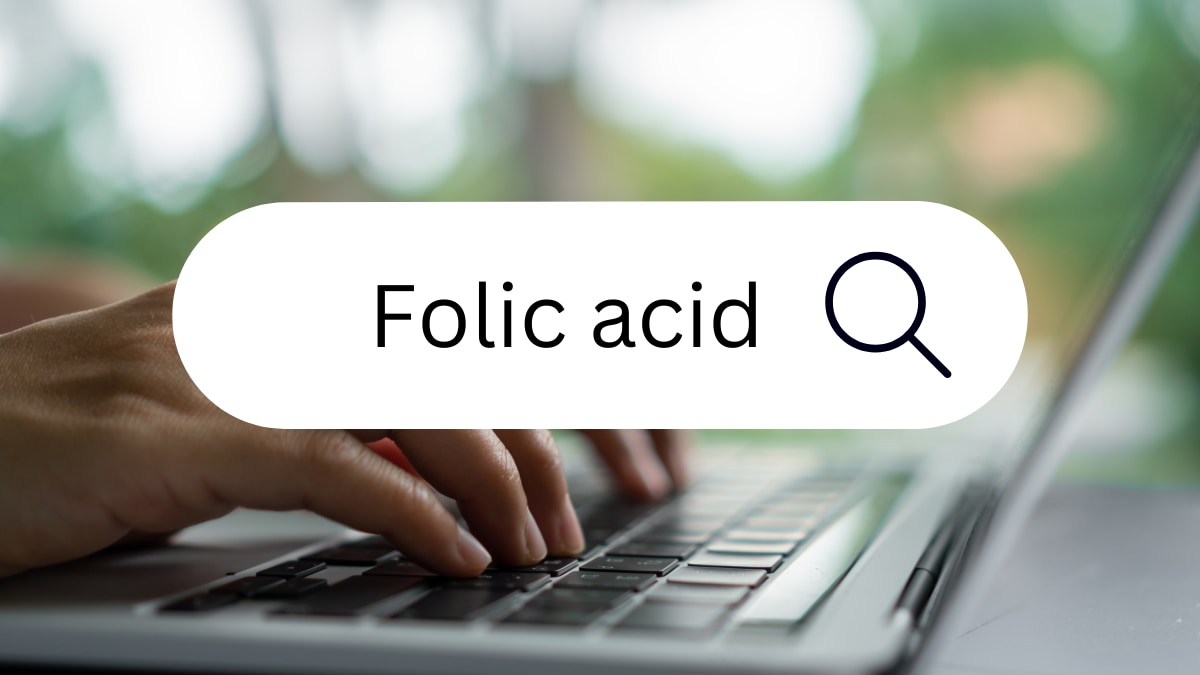 A person typing on a laptop with a search icon on the screen that reads "folic acid"