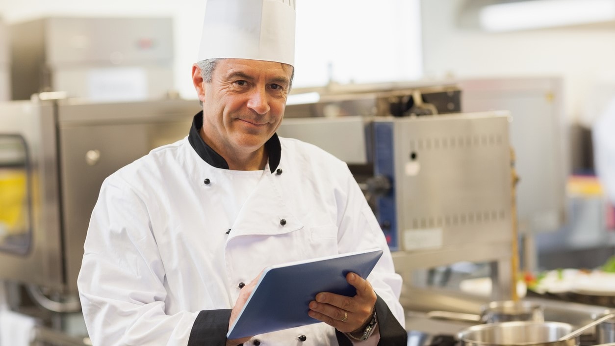 Chef with clipboard in commercial kitchen.