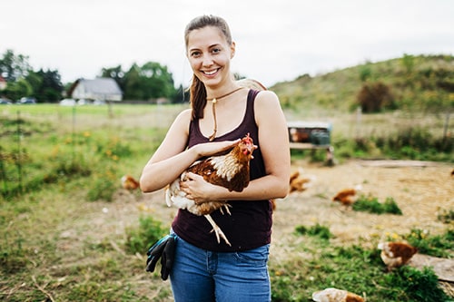 A woman is holding a chicken