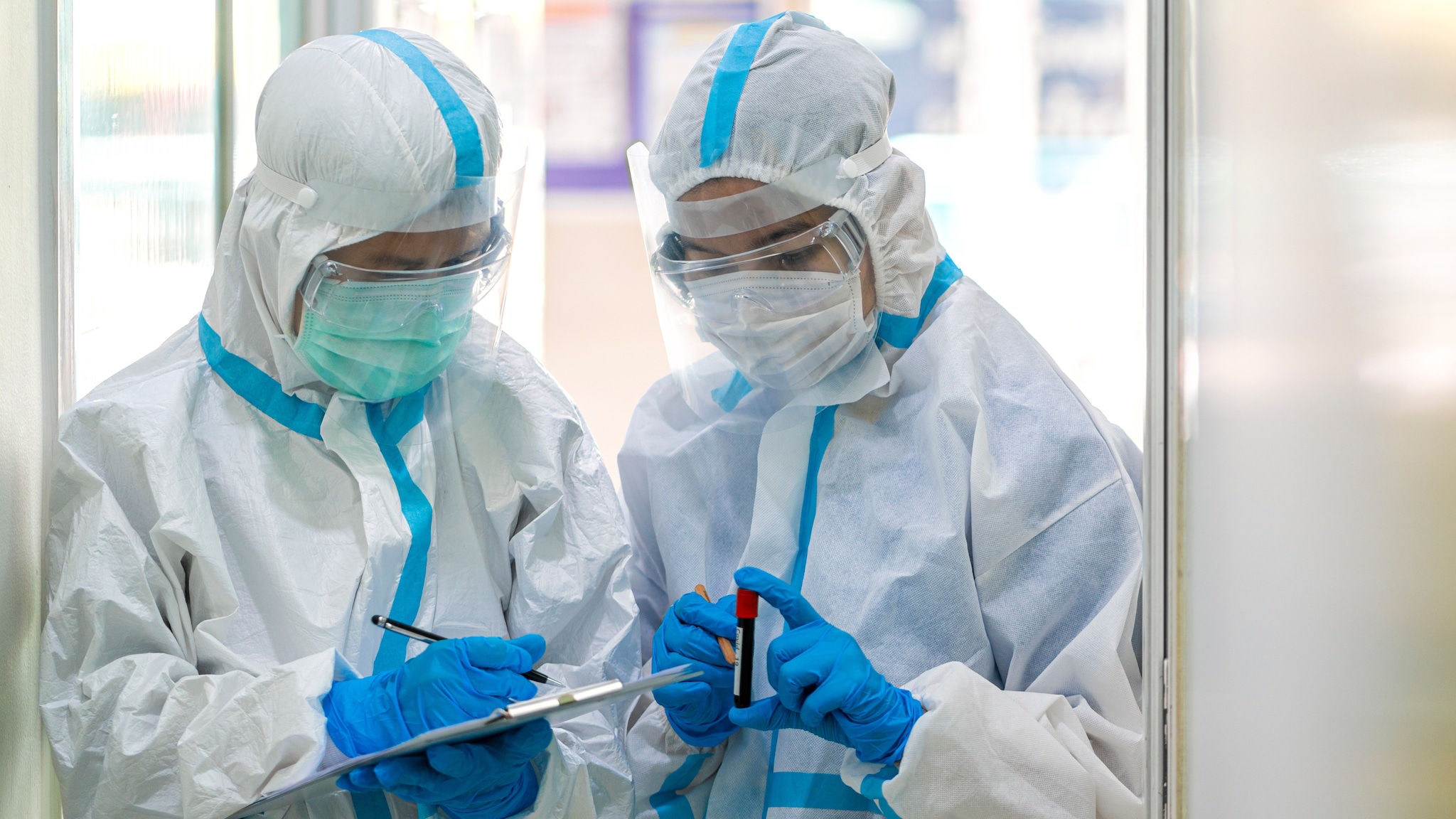 two people in a lab wearing ppe holding tubes of blood