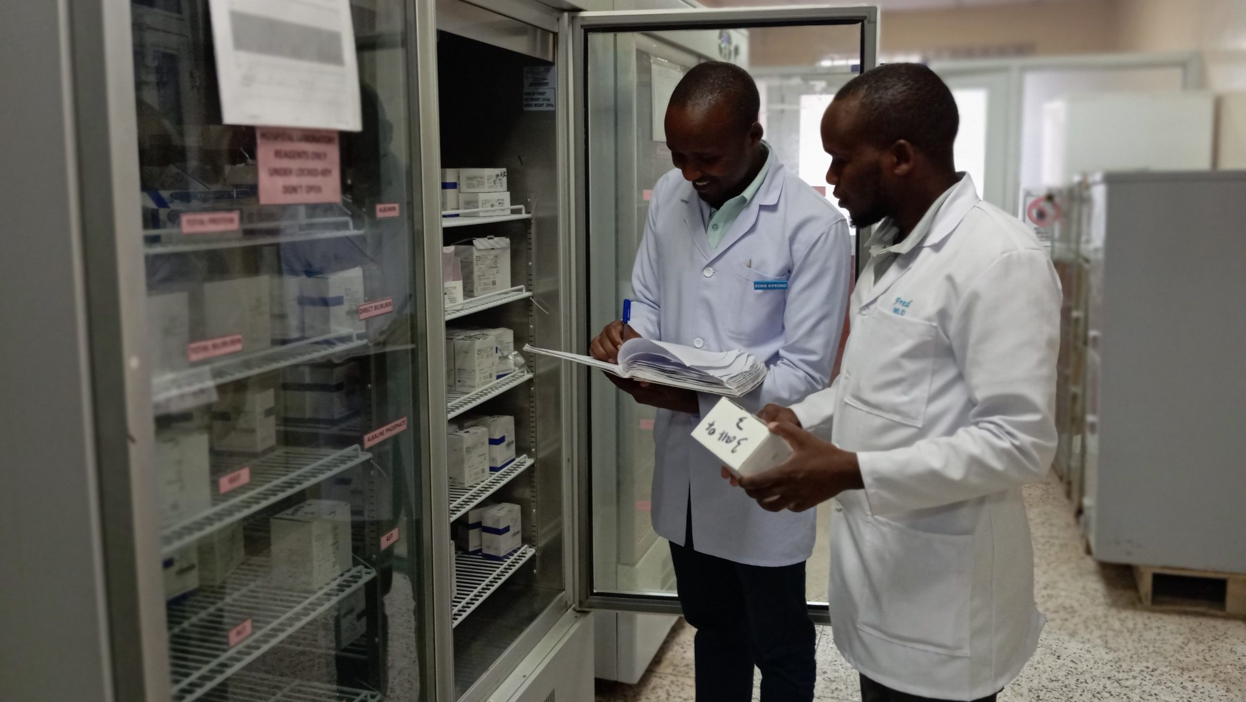 Two lab workers inventorying items in cold storage