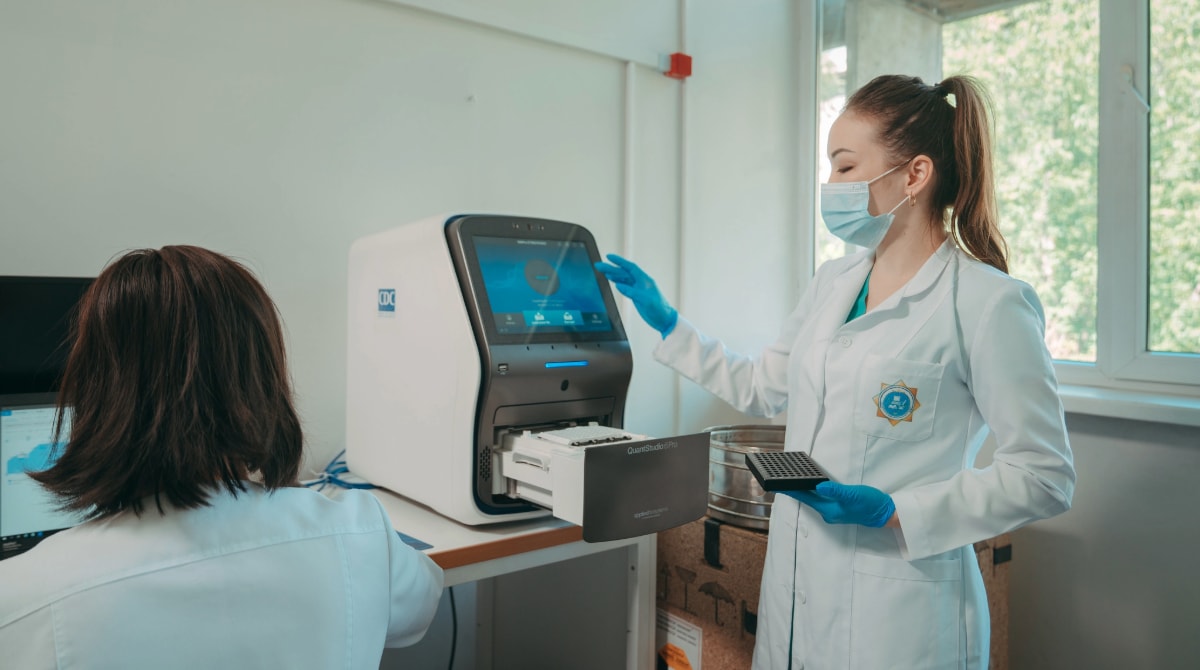 A microbiologist in a lab takes samples from a CDC-donated equipment.