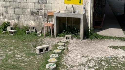 Stepping stones are painted with green and yellow pairs of feet and lead up to a handwashing station.